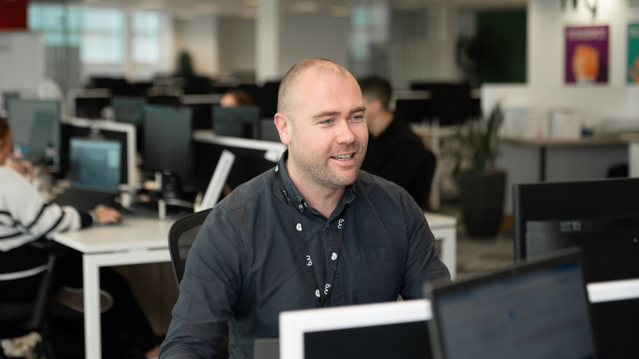 man smiling working at a computer in office