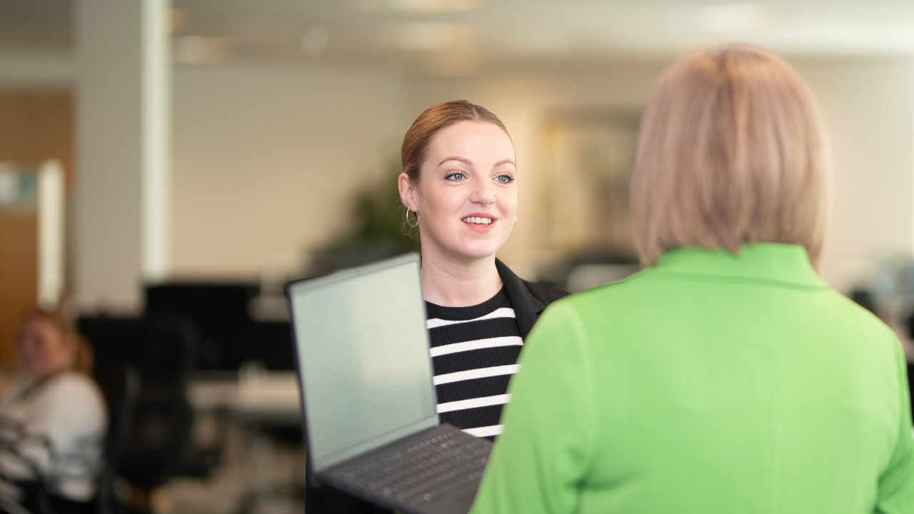 two people standing talking in office environment